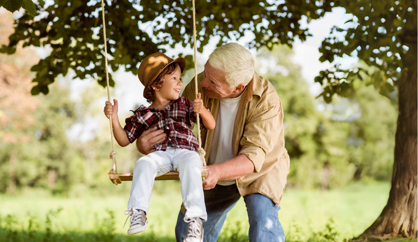 grandfather pushing boy on swing