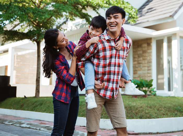 Young couple smiling in street in front of house