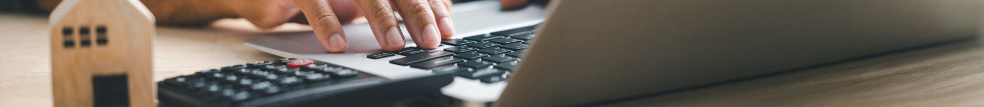 Man working on laptop with calculator on desk