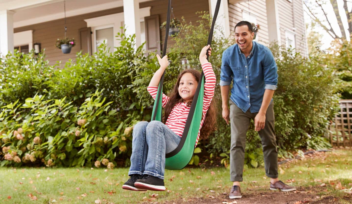father pushing daughter on swing.