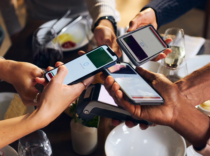 People holding cell phones together at dinner table
