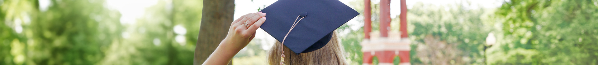 Young woman holding graduation cap and wearing graduation gown