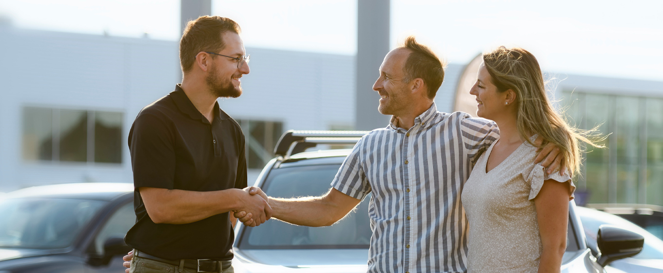 A couple shaking hands with an auto dealer