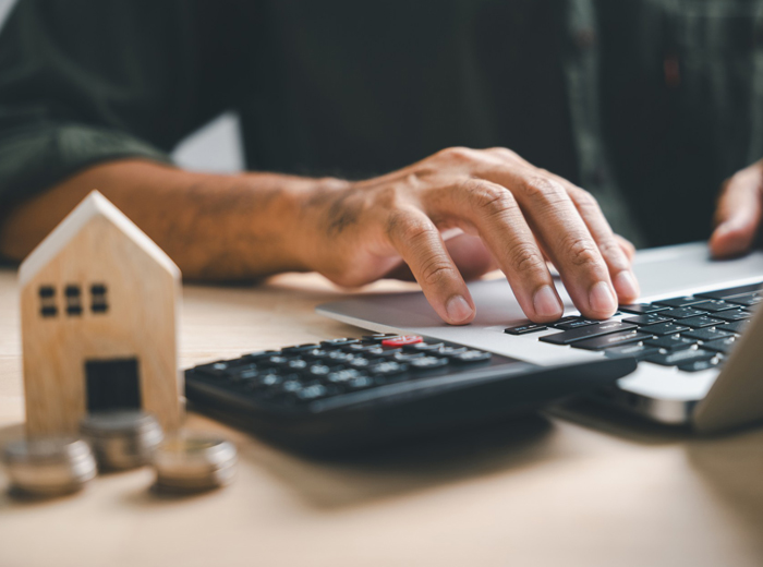 Man working on laptop with calculator on desk